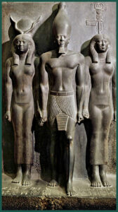 Gruppo statuario in scisto grigio del Faraone Menkaura/Micerino (con la corona bianca dell’Alto Egitto), con alla destra la Dea Hathor (che esibisce il cerchio solare tra le corna di vacca) e alla sinistra la personificazione di Kasa (Kynopolis) capitale de XVII “Nomo” dell’Alto Egitto).